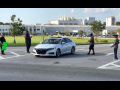 Workers outside a big plant approach a car with leaflets.