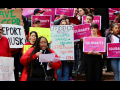 CFPB workers at a rally holding pink signs that say Solidarity and other handmade signs with slogans like CFPB Protects All Consumers.