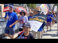 Actor Sam Humphrey and several others march towards the camera with ‘SAG AFTRA on strike’ and ‘Writers Guild of America On Strike’