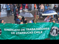 Five workers in the rain hold a green banner that says Chilean Starbucks Union in Spanish