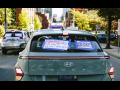 A car back window carries signs, including one saying, “Would you drive 10 miles for $4? Raise the Pay!”