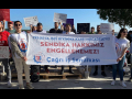 A group of 30 men and women with signs in Turkish stand outside behind a banner