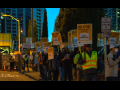 Picketers in yellow vests holding "ON STRIKE FOR FAIR WAGES AGAINST SELLER CONSTRUCTION" signs outside in dim dawn light.