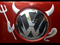 Devil horns, pitchfork, and tail have been added to the VW logo on a car