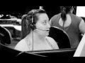 female call center worker with headset at cubicle, other workers in background