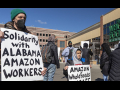 Adult and boy with signs in front of Whole Foods supporting Alabama Amazon workers attempting to unionize.