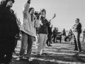 A vintage black-and-white photo shows a line of workers standing outside, one calling into a megaphone, facing down cops with folded arms. They are photographed from a low, dramatic angle.