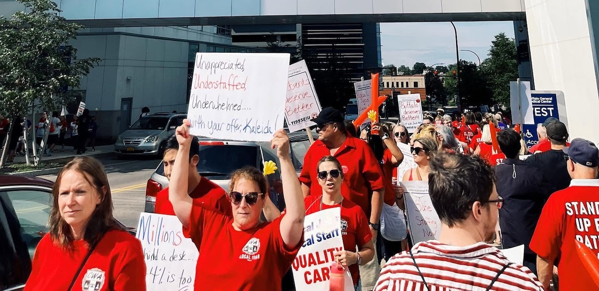 Red-shirted hospital workers march with signs.