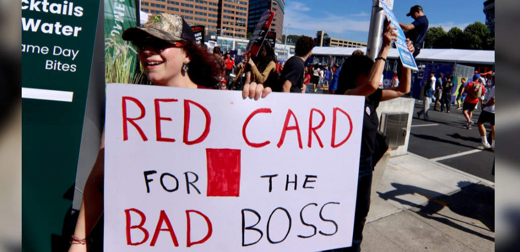 A worker holding a sign that says: Red card for the bad boss