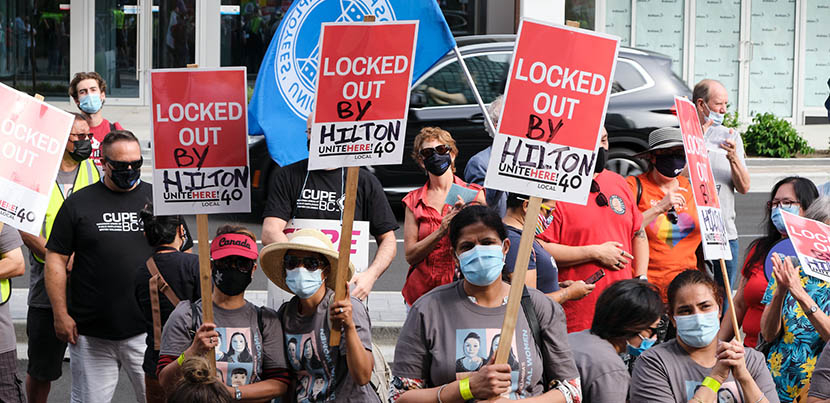 Hilton Vancouver Metrotown workers with signs fighting for their recall rights.