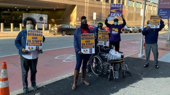 four protesters hold signs: "PROTECT VETERANS AND VA STAFF #VACOVID" AND "NAGE SEIU"