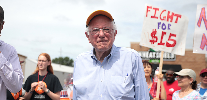 Photo of Bernie Sanders in front of Fight for $15 sign.