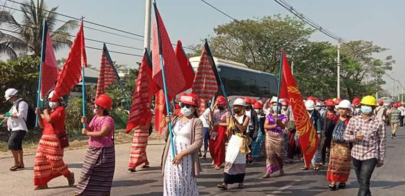 Women marching in the streets with red flags in Burma.