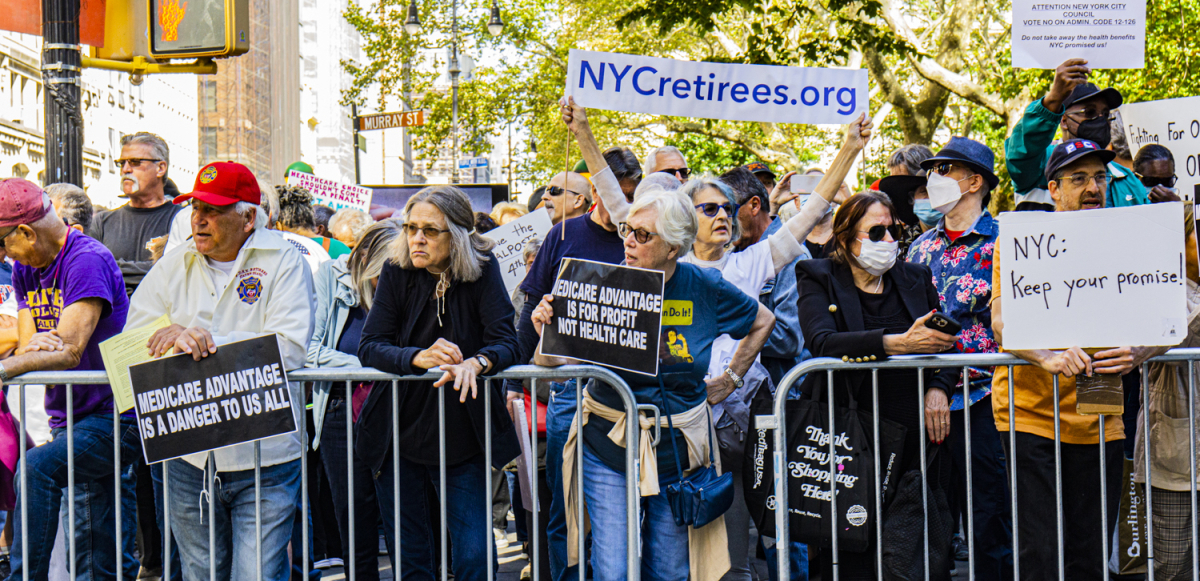 a line of retirees protest behind a metal barrier