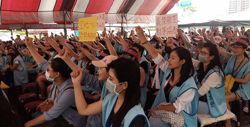 Taiwanese flight staff assembled in protest with arms raised.