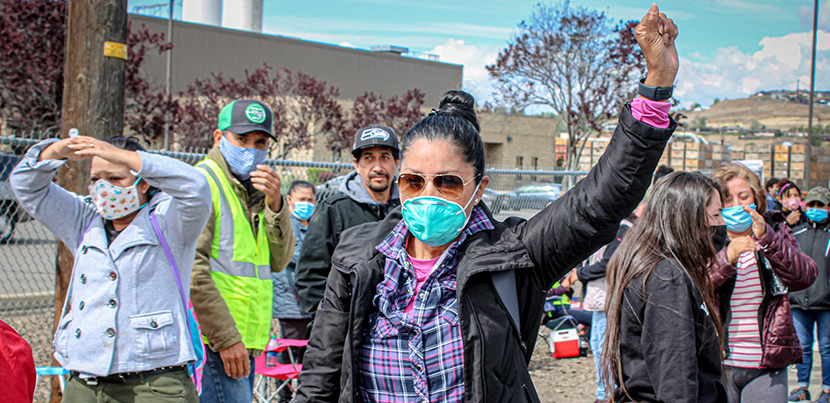 Woman with fist up amidst farmworkers on strike