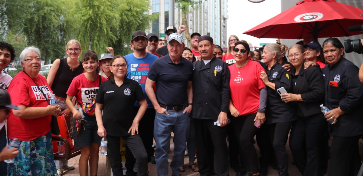 A group 25 of workers in red shirts gather near an umbrella saying Panda Express