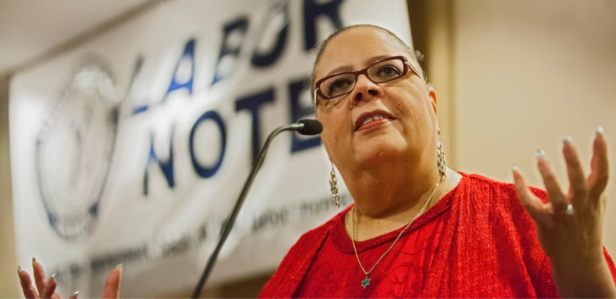 Karen Lewis at the podium in front of Labor Notes banner