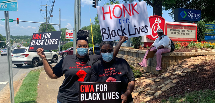 Two CWA members with signs for Black lives on the pavement