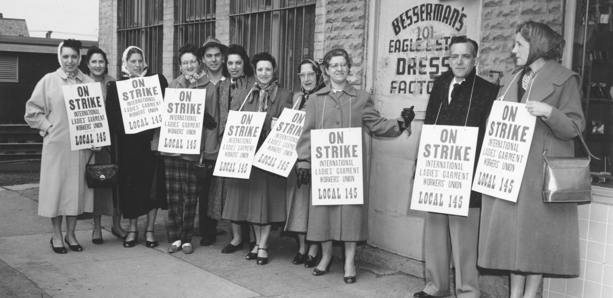 A group of striking garment workers stand in front of their factory in 1958.