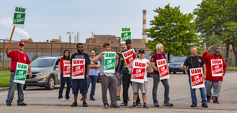 GM strikers picketing on the road holding signs.