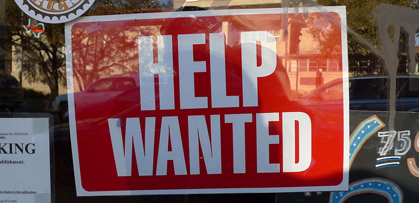 Help Wanted sign - background red, text white, in window of store