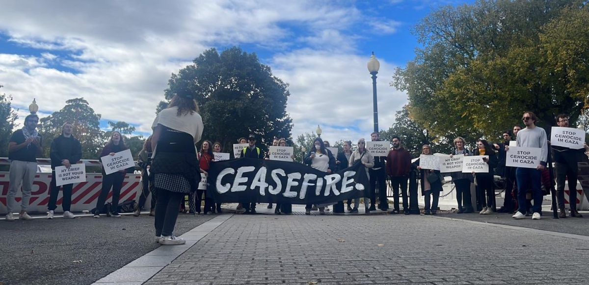A group of people hold a black banner that says CEASEFIRE.