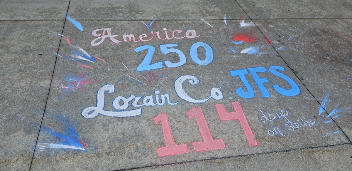 Chalk graffiti on sidewalk says “America 250, Lorain Co. JFS 114 days on strike”