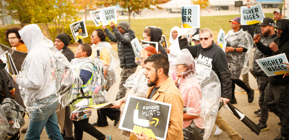 Amazon workers march holding signs that say higher wages. 