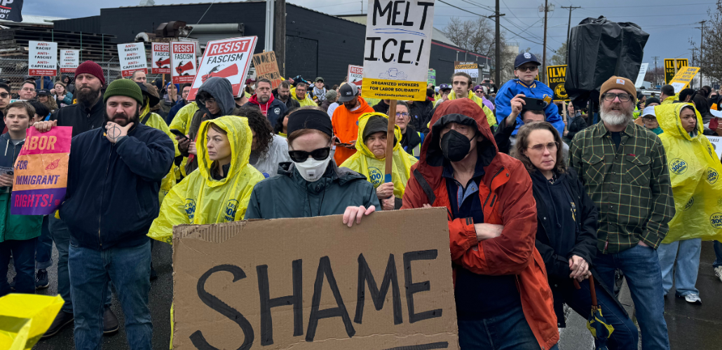 Workers gather in a March 27 protest holding signs reading "Shame" and "Melt ICE!"