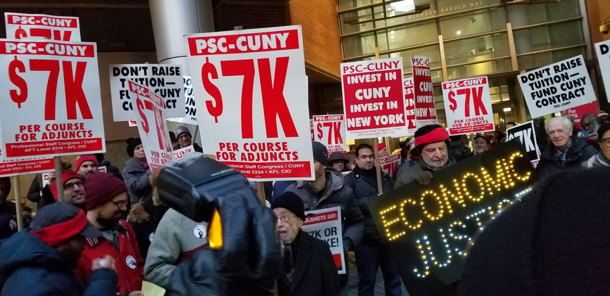crowd holding signs including "PSC-CUNY $7k per course for adjuncts," "invest in CUNY, invest in New York," and "ECONOMIC JUSTICE" spelled out in lights