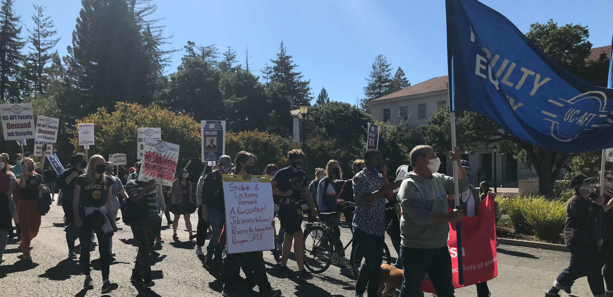 A group of students and lecturers march holding banners and signs.