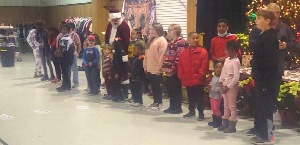 Kids stand in a row, with Santa among them, inside the union hall at a Christmas function