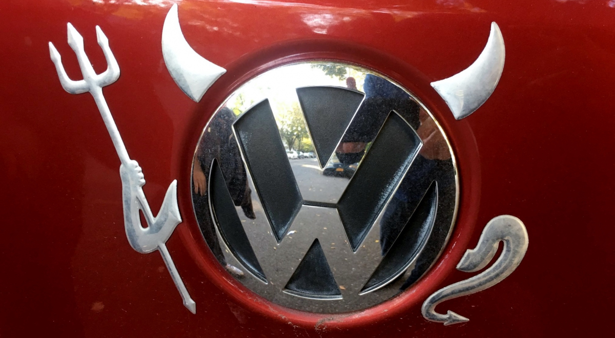 Devil horns, pitchfork, and tail have been added to the VW logo on a car