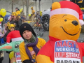 A line of children and adults push baby carriages with inflatable animals wearing signs saying ‘Macy’s Workers on ULP Strike’