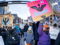 Marchers bundled against the cold carry colorful signs
