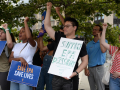 Several people raise their fists, one holds a homemade sign saying “support EPA dissent”
