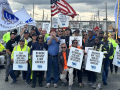 Thirty workers with ILA flags line up for the camera, smiling and waving signs