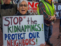 A woman holds a sign at a rally that reads Stop the Kidnappings! Protect Our Neighbors!