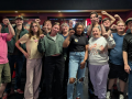 About 15 members of UFCW Local 8 pose for a photo at a bowling alley with their fists raised.