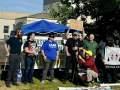 Ten people, some with Machinists Union shirts, stand with a Machinists Local 160 banner