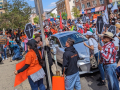 A crowd fills the street holding signs, some of them shaped like coffins.