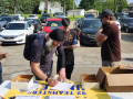 A group of Teamsters in a parking lot stand around a table with petitions and leaflets on it. One is filling out a sign-up sheet.