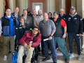 A group of 10 people poses for the camera. One is in a wheelchair.