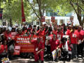 A large group wearing red with banners and signs and flags pose for the camera