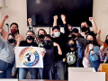 A crowd of Starbucks workers and other Workers United members celebrate with arms raised, posing for photo