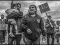 Lelo Juarez stands with his wife and child at a May Day march. Behind him, someone holds a sign reading "without fear" in Spanish. 
