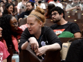 Two women talk across seats in filled auditorium.