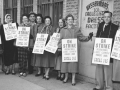 A group of striking garment workers stand in front of their factory in 1958.