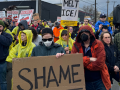 Workers gather in a March 27 protest holding signs reading "Shame" and "Melt ICE!"